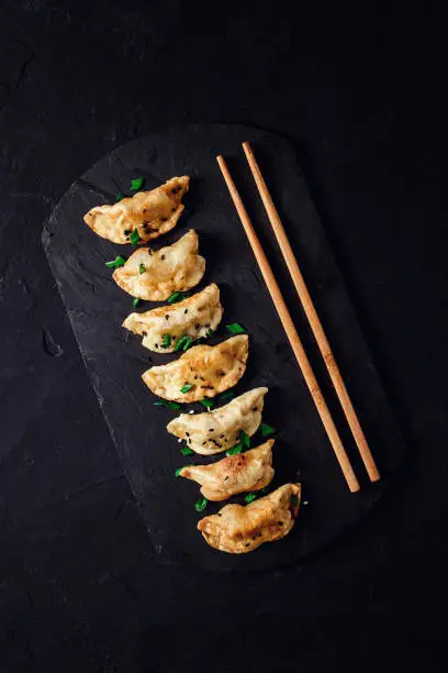 Japanese Gyoza dumplings ,fried, with sauce, on a black background, top view, no people, toned,boiled, selective focus