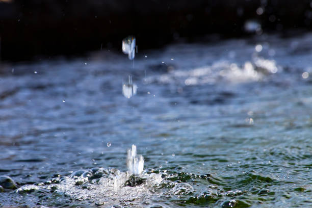 Water surface and two spurts splashing on it, granite stone edge , focus in the  foreground, seen along the Camino de Santiago ancient pilgrimage route, Boente, Arzúa, Galicia, Spain.