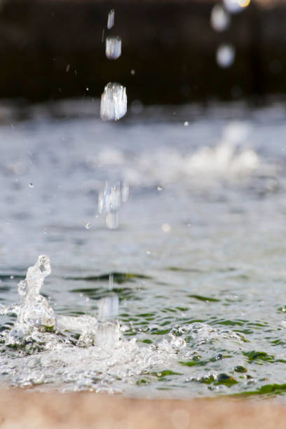 Water surface and two spurts splashing on it, granite stone edge , focus in the  foreground, seen along the Camino de Santiago ancient pilgrimage route, Boente, Arzúa, Galicia, Spain.