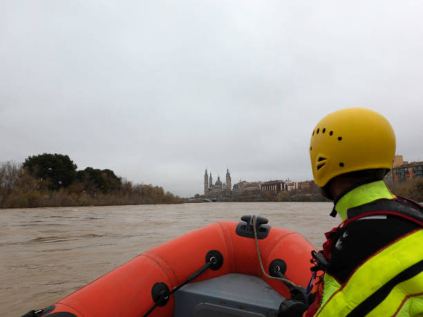 istock rescuer watches the river during a flood while riding in a boat 1360835103