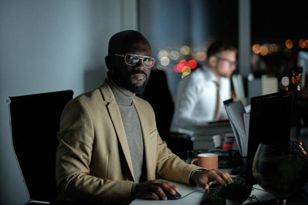 istock Young African broker in formalwear sitting in front of computer 1360841072