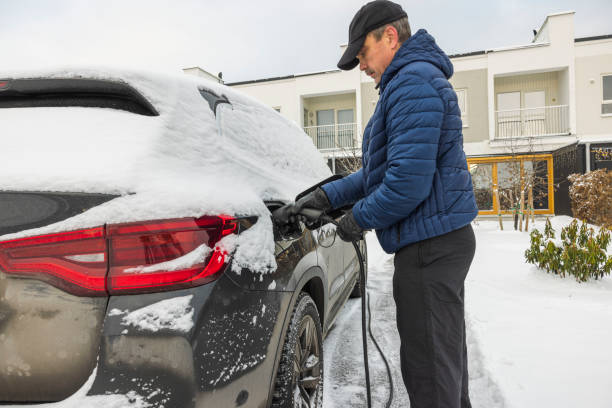 bella vista di un uomo che collega un cavo di ricarica a una stazione di ricarica per auto elettriche in una gelida giornata invernale. svezia. - snow nature sweden cold foto e immagini stock