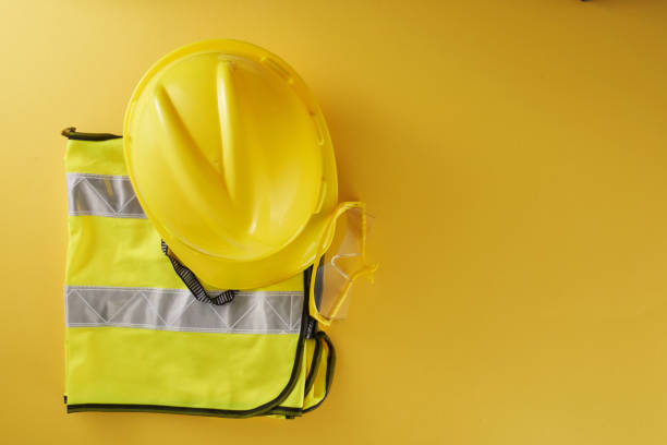 istock Yellow Hardhat , Safety Glasses and reflective vest on yellow background 1360842012