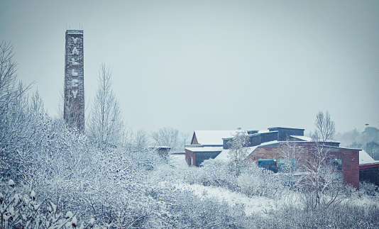 Toronto, Ontario/Canada - November 28, 2021:  Old factory buildings and chimney with Valley sign in Evergreen Brickworks, view from Don Valley Brick Works Park, Toronto, Canada in winter snow.