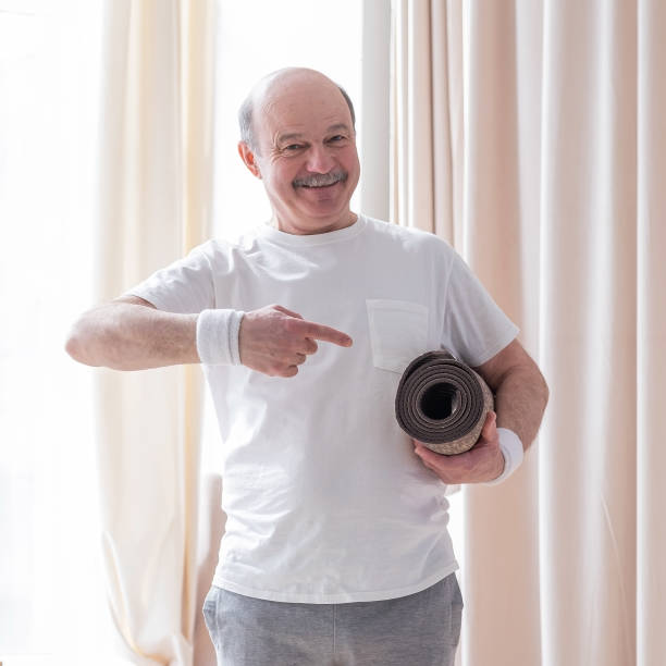 istock Senior man with a yoga mat looking at camera with smile 1360848395