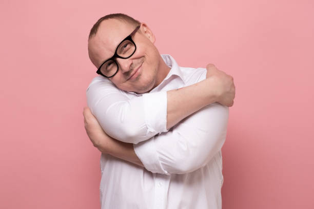 istock Mature caucasian man hugging himself against pink background 1360851329