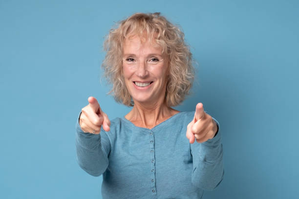 Cheerful senior woman pointing to you. She is afgree with your plan. stock photo