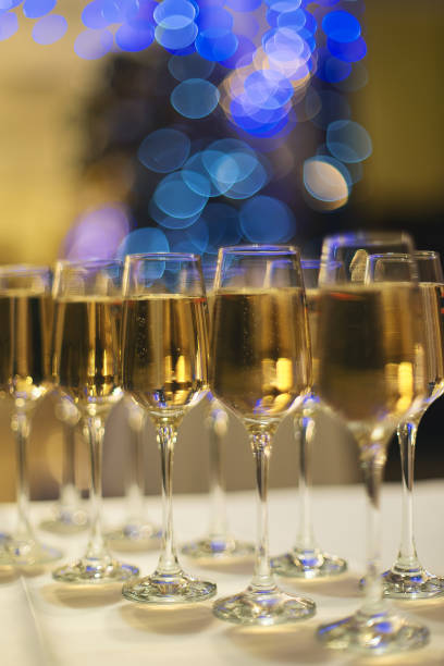istock Glasses with sparkling wine on a bokeh background from blue garlands on a festive table 1360853986