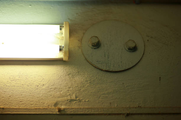 istock fluorescent lamp and a metal plug on the wall, close-up. 1360854814