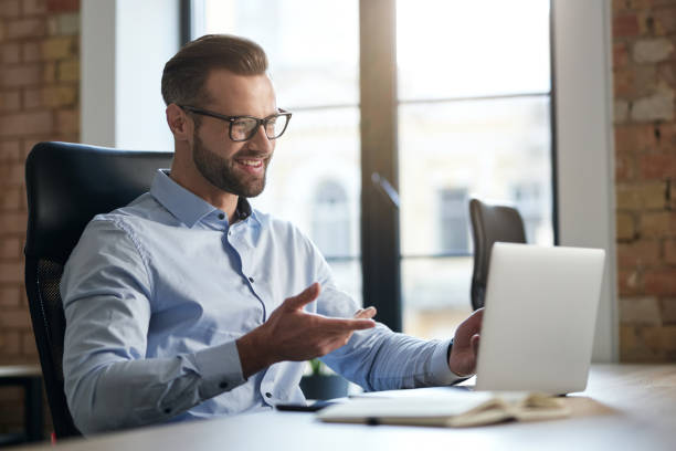 istock Mirthful employee looking at the laptop screen and smiling 1360856054