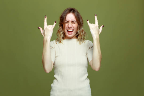 Exited cool young woman show rock n roll gesture by raised hands, screaming. Female rocker music fan celebrate success Exited cool young girl show rock n roll gesture by raised hands, screaming. Female rocker music fan showing horns sign by fingers, yelling closed eyes feel delight. High quality photo rock musician stock pictures, royalty-free photos & images