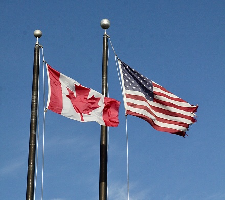 Canadian and American flags flying near the countries border