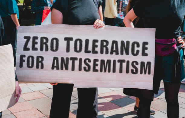 la frase " tolleranza zero per l'antisemitismo " disegnata su uno striscione di cartone in mano. una ragazza tiene un cartone con un'iscrizione. ragazze per strada. protesta, marcia. radunare. - anti semitism foto e immagini stock