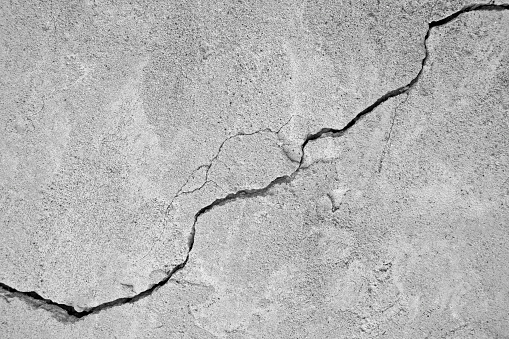 Big winding ascending crack on an old concrete wall, thin crack diagonally. Close-up. Selective focus. Copy space.