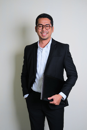 Young Asian business man smiling confident while holding laptop computer