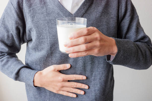 A person who holds a glass of milk in one hand and holds his stomach stock photo