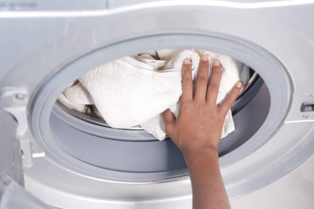 istock putting towel and cloths in a washing machine. 1360892611