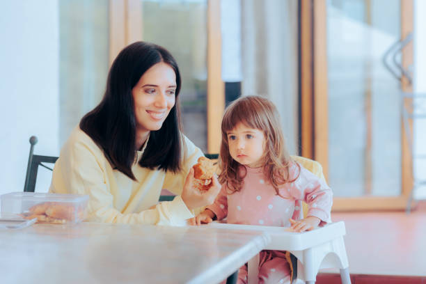 レストランでマフィンを持つハイチェアに座っている小さな女の子 - muffin freedom breakfast photography ストックフォトと画像