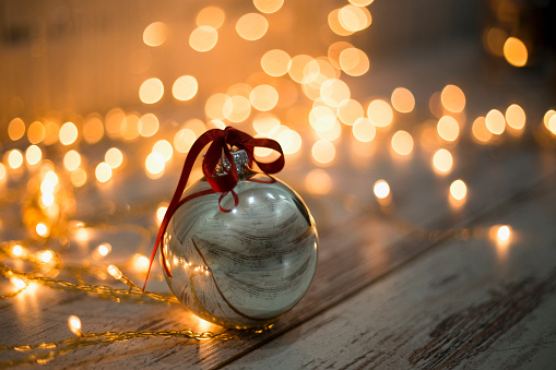 Two golden  Christmas balls on a background of garland shining lights and snow. Christmas decor background, backdrop, banner, header with copy space for text.