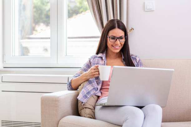 istock Nice beautiful lady with black hair work at the notebook sit down on the sofa at home - check on oline shops for cyber monday sales - technology woman concept for alternative office freelance 1360923568