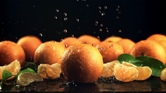 Drops of water fall on ripe tangerines. Filmed is slow motion 1000 frames per second.