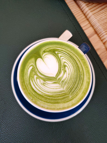 Matcha Latte on leather mat, on wooden background