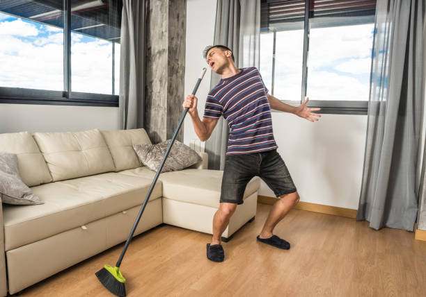 istock Singing man holding broom as if it were a microphone. 1360928549