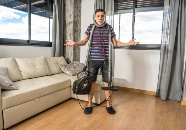 istock Man trying to understand how a vacuum cleaner works. 1360928579