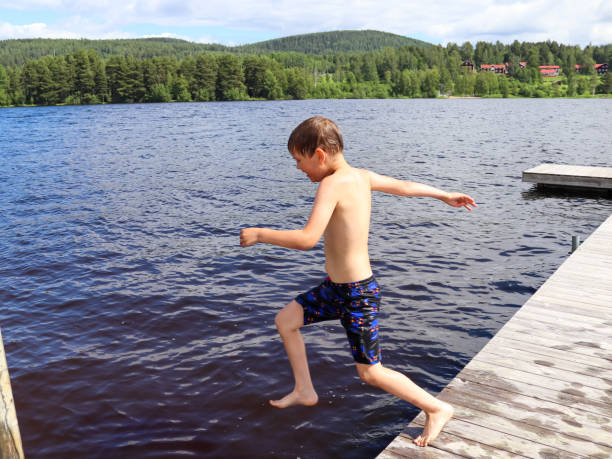 istock Young boy jumping into the water from jetty 1360930874