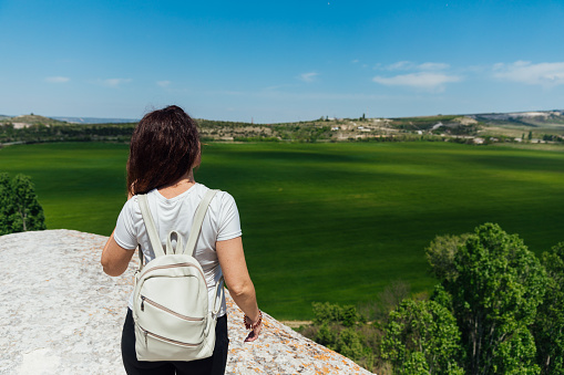 woman looks at the landscape from the top of the mountain