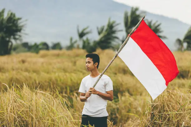 Photo of asian young adult holding indonesia flag in the village