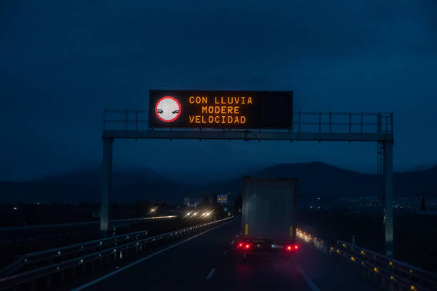 istock Illuminated panel of a highway on a rainy night with the legend 