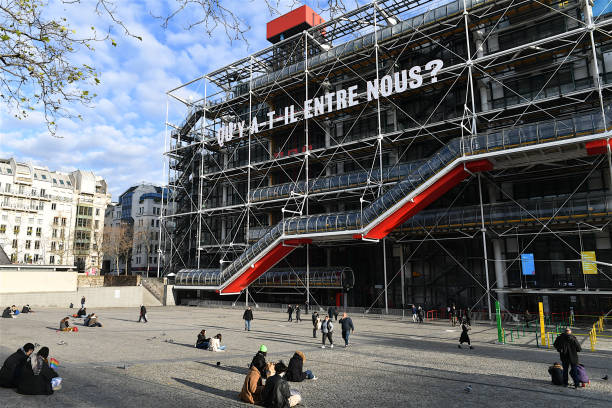 The Pompidou center, Paris, France. Paris, France-12 23 2021:People sitting and walking past the Centre Pompidou in Paris, France.The Pompidou Center, is a complex building in the Beaubourg area, near Les Halles. With over 100,000 works, the collections of the Musée National d'Art Moderne make up one of the world's leading references for art of the 20th and 21st centuries. pompidou center stock pictures, royalty-free photos & images