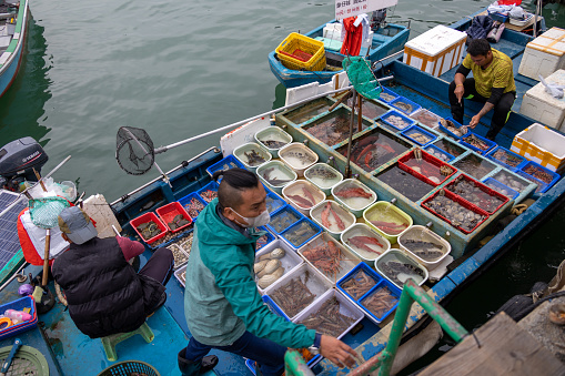 Hong Kong - December 26, 2021 : Fishermen doing business at a floating seafood market in Sai Kung Pier, New Territories, Hong Kong. It is famous for its seafood market and restaurants in the fishing village, Hong Kong.