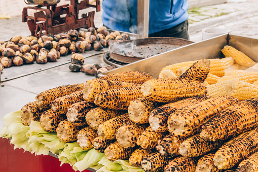 Grilled street corn, roasted corn - popular autumn and winter street food around the world. Traditional winter delicacy. Healthy street food, selective focus