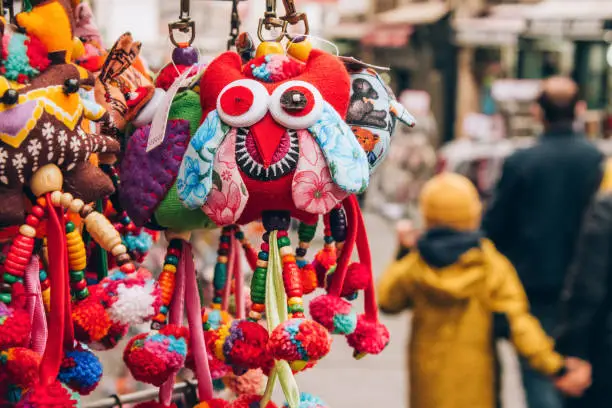Photo of Souvenir stall with variety of colorful souvenir toys and amulets, street souvenir market. Popular touristic present. Selective focus