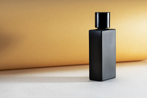 Black bottle with perfume on a yellow background