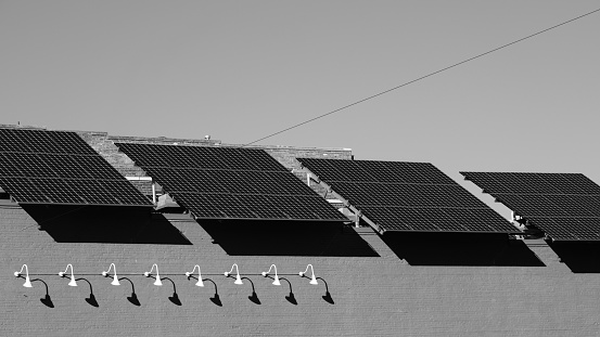 Solar panels and light fixtures on facade of building in monochrome
