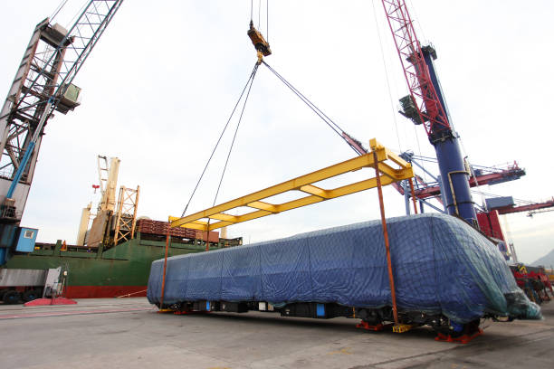 Transportation of old mobile tower crane with waste tyres to repair station on long cargo platform of truck trailer. Lorry delivery truck, cargo roadtrain for heavy machinery vehicles carriage.