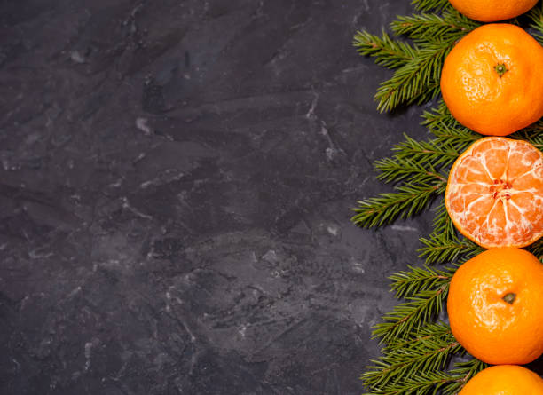 istock Christmas composition with tangerines on black background, with green spruce tree branch. Flat lay 1361028401