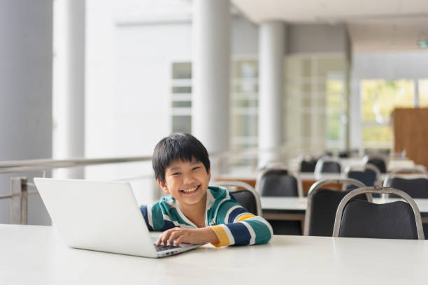 istock Portrait of Cute Asian boy studying or playing game with laptop computer 1361031961
