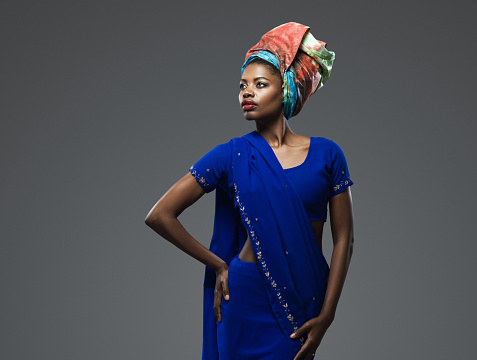 Portrait of beautiful African American female wearing a traditioanal African dress and African headwrap over isolated gray background. Image taken with Hasselblad H5D 50C camera system and developed from camera RAW.