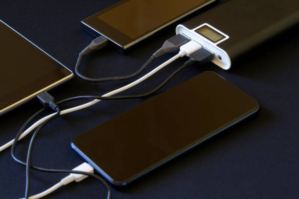 istock An external battery - a powerbank with three gadgets connected to it lies on a dark background. The concept of recharging a variety of smart devices 1361035538