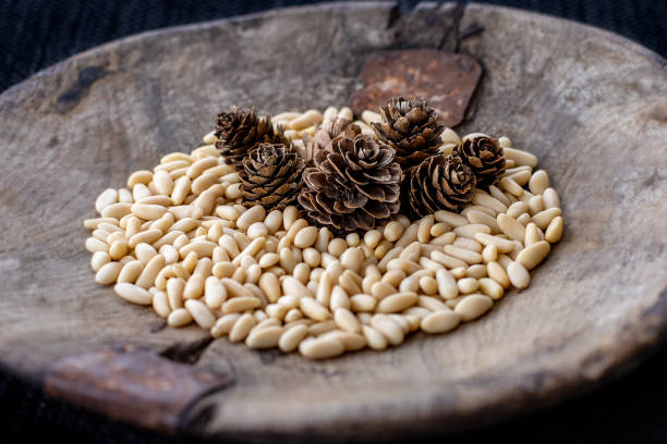 pinoli e pigne in ciotola di legno. - pine nut nut isolated pine cone foto e immagini stock