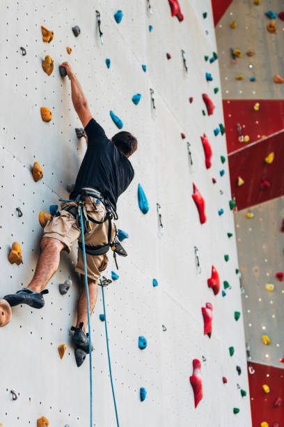 istock Sportive man climbs up on artificial rock wall 1361041562