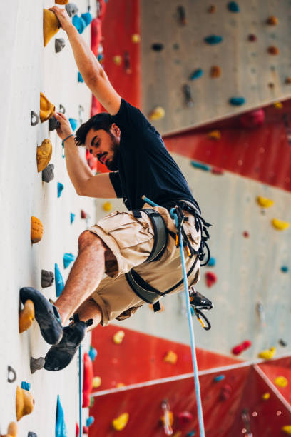 istock Young man climbing artificial rock wall at gym 1361041568