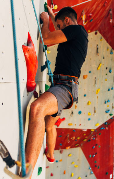 istock Sportive man climbs up on artificial rock wall 1361042094