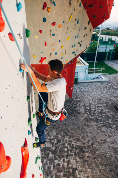 istock Sportive man climbs up on artificial rock wall 1361048996