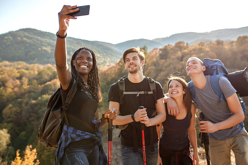 Happy group of friends taking a selfie on a hike with beautiful landscape