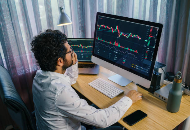 istock Businessman analyzing crypto currency market graphs on computer and laptop screen at home. Bitcoin / Cryptocurrency concept 1361055380